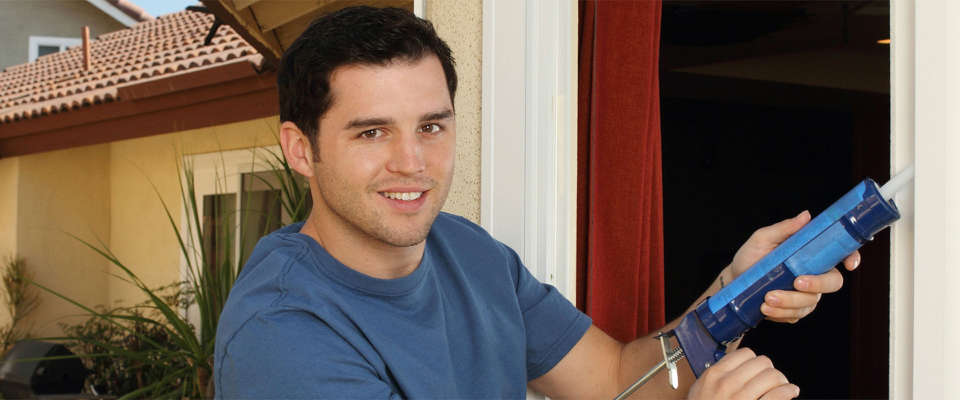 Energy-Saving-Tips Man caulking doors and windows